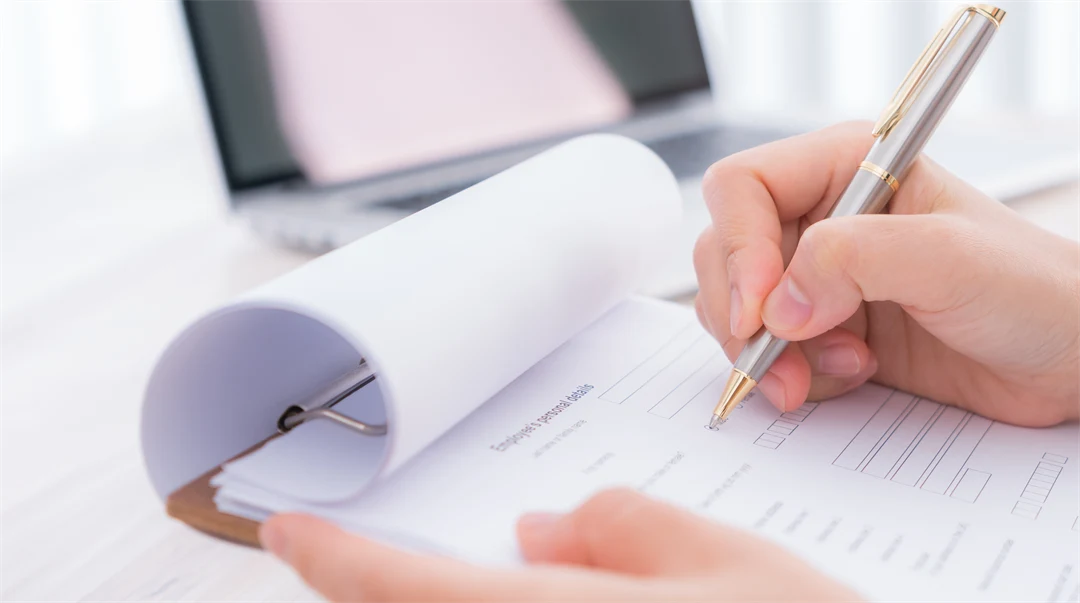 Hand with pen over assessment form.